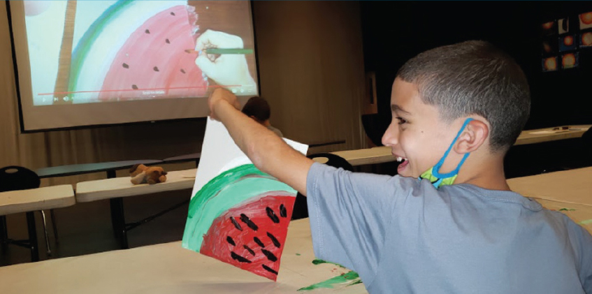 Boy holding a painting of a watermelon at the Boys & Girls Club of Geneva